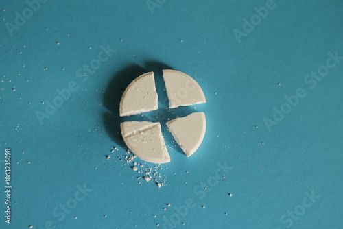 Photos a closeup shot of a white pill on a blue surface