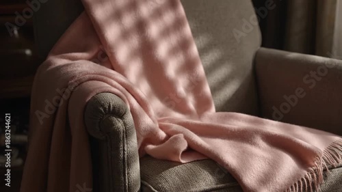 Soft Pink Throw Blanket Draped Over an Armchair in Morning Sunlight.