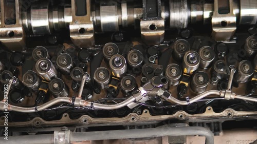 The camshaft and valve train components of a car engine. Mechanics inspect and document metal engine components. An engine mechanism on a work bench in a workshop during professional auto repair.