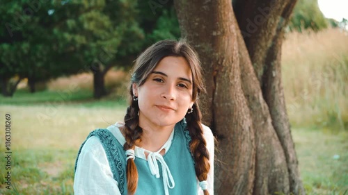 Portrait of a beautiful young woman smiling at the camera. Cheerful person standing outdoors in a park on a sunny day.