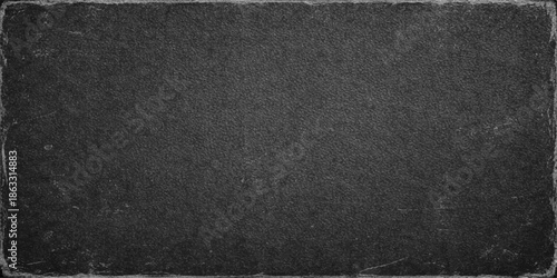 A dark macro shot of a rough black leather material texture featuring a grunge pattern surface that resembles a grey asphalt road backdrop for a textured textile wallpaper design
