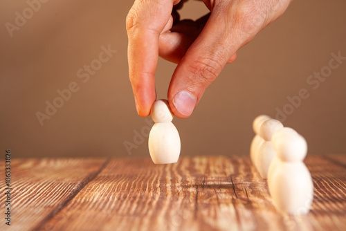 The hand of a man puts a wooden pawn on a wooden table.