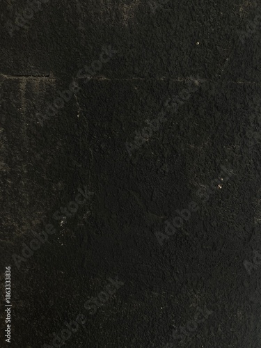 Grunge black rocky wall texture with natural cracks and rough surface details