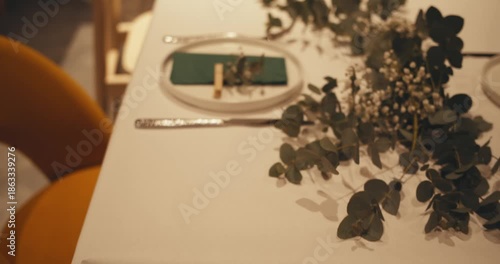 modern elegantly set table in luxurious expensive Michelin restaurant. plates napkins, cutlery and decorations fresh flowers and plants on table. delicate pastel green decoration for dinner atmosphere