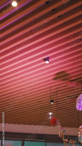wooden plank ceiling in room or cafe and decorations for children birthday party. part of modern minimalist interior in food catering establishments. lighting effects in room pink light shines upwards