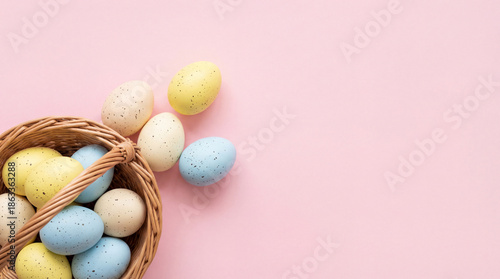 An overhead shot of a woven basket brimming with pastel-colored eggs, perfectly captured against a soft pink backdrop, creating a simple, charming, and symbolic composition.