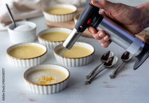 Canvas-taulu Preparing Creme Brulee dessert ramekins with a torch for browning the sugar