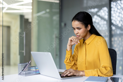 Картината върху платно Woman in a professional yellow shirt concentrating on her work, sitting at a des