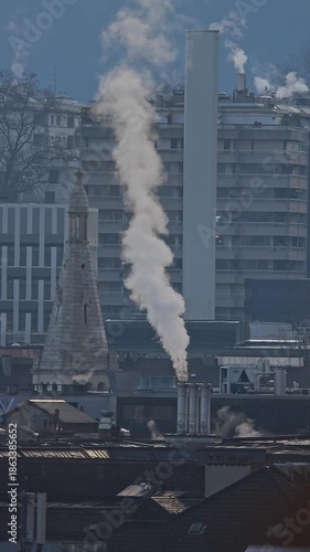 Urban heating and chimneys in Geneva cityscape, Switzerland. Energy consumption and steam rising from city rooftops in winter. Vertical video