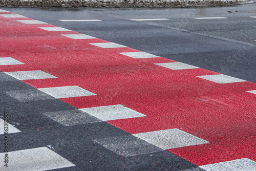 Warsaw, Poland, January 01, 2025. Red and white striped pedestrian crossing markings painted on asphalt road surface in winter. High quality photograph