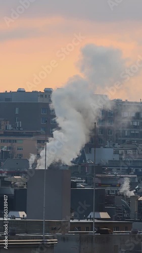Urban Energy Consumption and Emissions during Golden Hour - Vertical video of Geneva, Switzerland. Cityscape at Sunset with Smoke Rising from Rooftops
