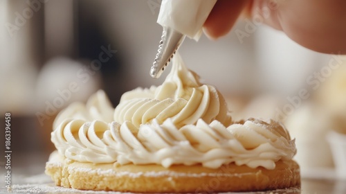Close-up view of a pastry chef decorating a dessert with white cream using a piping bag