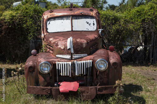 Rusty weathered pickup truck front detail in grassy field
