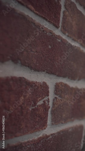 Close up of a red brick wall with visible mortar lines. Camera moves from left to right, revealing textured surface and construction details. Architectural background, building material concept. Loft