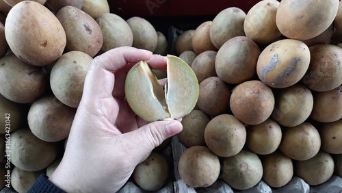Close-Up of Hand Holding Cut Fresh Sawo or Sapodilla Fruit