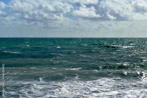 Waves on the sea with wind turbines (offshore wind farm) on the horizon, The English Channel, Brighton, England, UK