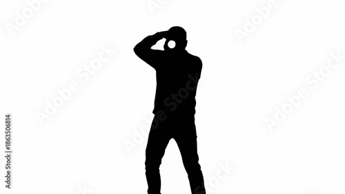 Silhouette of a person wearing headphones and holding a camera.