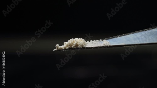 Lethal dose of fentanyl on the tip of craft knife blade. Two milligrams of fentanyl is lethal dose for humans. Tiny pile of powder to give a sense of scale. Synthetic narcotic analgesic drug.