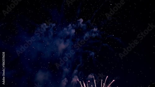 Vibrant pink and purple fireworks exploding in night sky with smoke