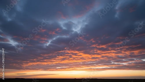 Vibrant sunset paints the sky with fiery orange clouds over a tranquil horizon