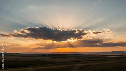 Scenic view of sunbeams breaking through clouds during sunset over a vast, open landscape