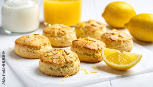 Lemon scones with almond slices, juice, lemons, & dairy on a white surface