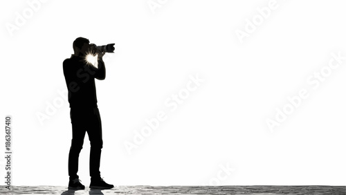 Silhouette of a photographer holding a camera and taking a photo.