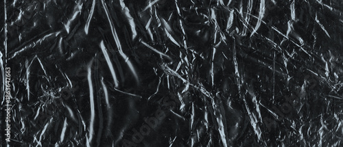 Wrinkled plastic wrap texture on a black background. Cellophane package wallpaper