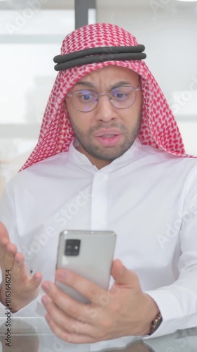 Young Muslim Man Upset by Online Trade on Phone, vertical video