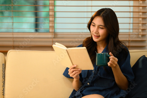 Foto Smiling Asian woman spends a peaceful moment at home, reading and sipping coffee