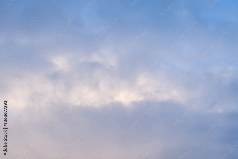 Fototapeta premium Gentle pastel clouds drift across a serene blue sky, creating a peaceful and airy atmosphere with subtle gradients and diffused light.