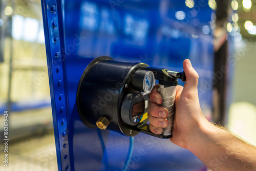 Aircraft mechanic testing rudder flexibility and structural integrity using a digital pressure-measuring device for aviation safety compliance and flight control assessment.