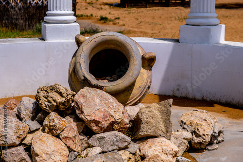 A large clay jug in the park on the ground.