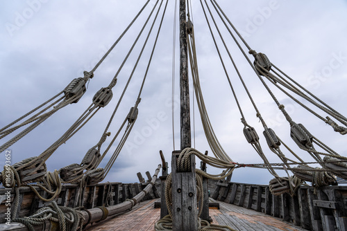 Close-up of Antique Sailing Ship Mast and Intricate Rigging Detail against Dark Overcast Sky, Representing History, Travel, and Nautical Heritage.