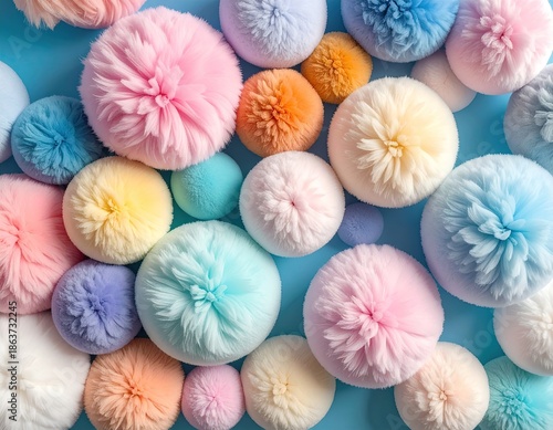 A vibrant close-up of fluffy, colorful pom-poms on a baby blue surface