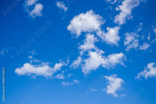 Φωτογραφία Soft white clouds are dispersed across a vivid blue sky, creating a minimal and uplifting natural scene