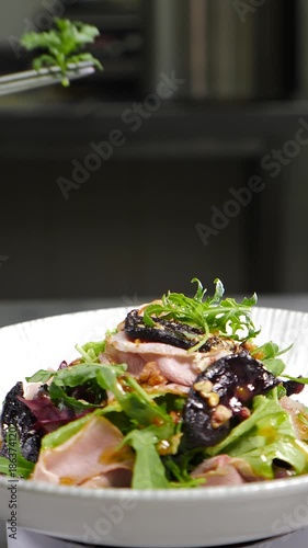 Final touch in dish serving. Cooking process. Luxury restaurant. Chef finishing duck dish with salad leaf. Serving plate with micro greens. final ingredients. restaurant kitchen. Vertical 4 k video