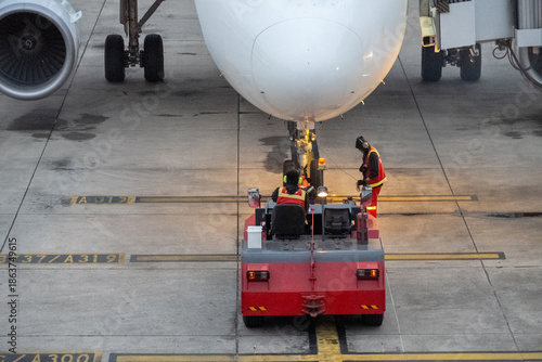 A red and white airplane with a man in a red vest and a yellow helmet