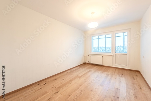 Bright Empty Room With Wooden Flooring and Large Window Overlooking Urban Scenery