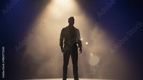 Man Stands Under Spotlight on Stage Giving Performance in Silhouette