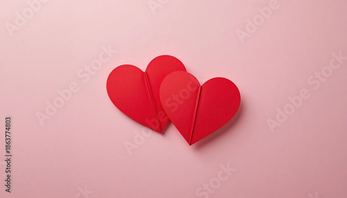 Minimalist design featuring three red paper hearts on a soft pink background for valentine's