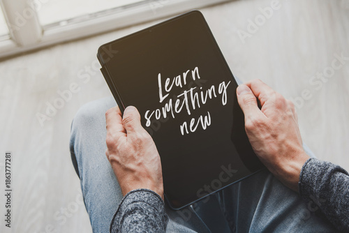 Photos Hands holding tablet with learn something new text on screen education motivatio