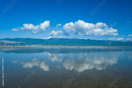 Obraz na plátne White cumulus clouds are reflected on the calm surface of the Missolonghi salt marsh in western Greece
