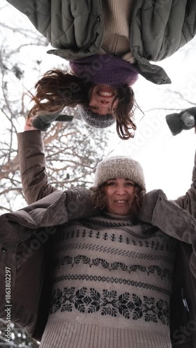 Two cheerful female friends are having fun and laughing in a winter park. The camera is facing upwards.