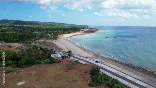 Wallpaper Mural Aerial drone footage of a costal road, with a white sand beach, blue sea, and a vast forest behind, in Sabu island, Indonesia Torontodigital.ca