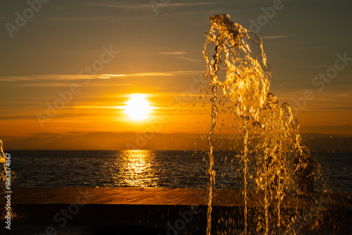 Golden sunset with fountain by the sea