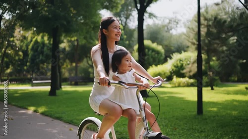 A heartwarming image of a mother and child enjoying a bicycle ride in a park. They are sharing a moment of joy and connection amidst nature Stock Video