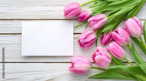 Pink tulips arranged beautifully beside a blank card on a rustic wooden surface, creating a serene and inviting atmosphere for personal messages or greetings