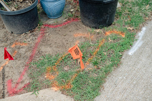 Bilde på lerret Planting pots near marked ground area shows red, orange utility flags and spray