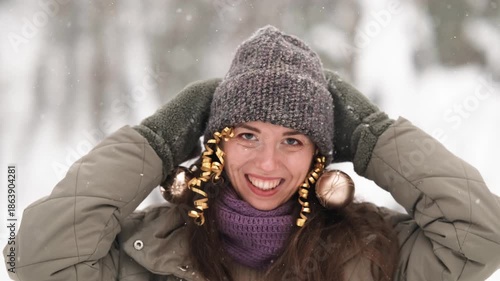 A beautiful young woman in winter clothes is happily spending her free time in a snowy forest. She enjoys the first snow. Active winter recreation.